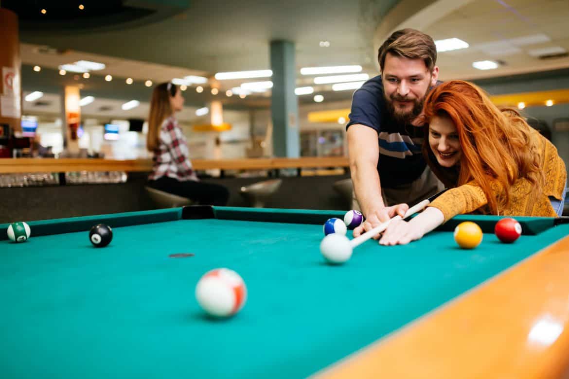Couple playing billiards on pool table