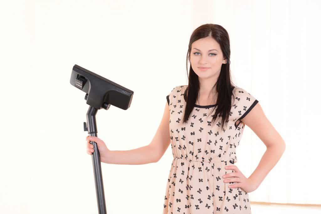 Beautiful young woman with vacuum cleaner in room