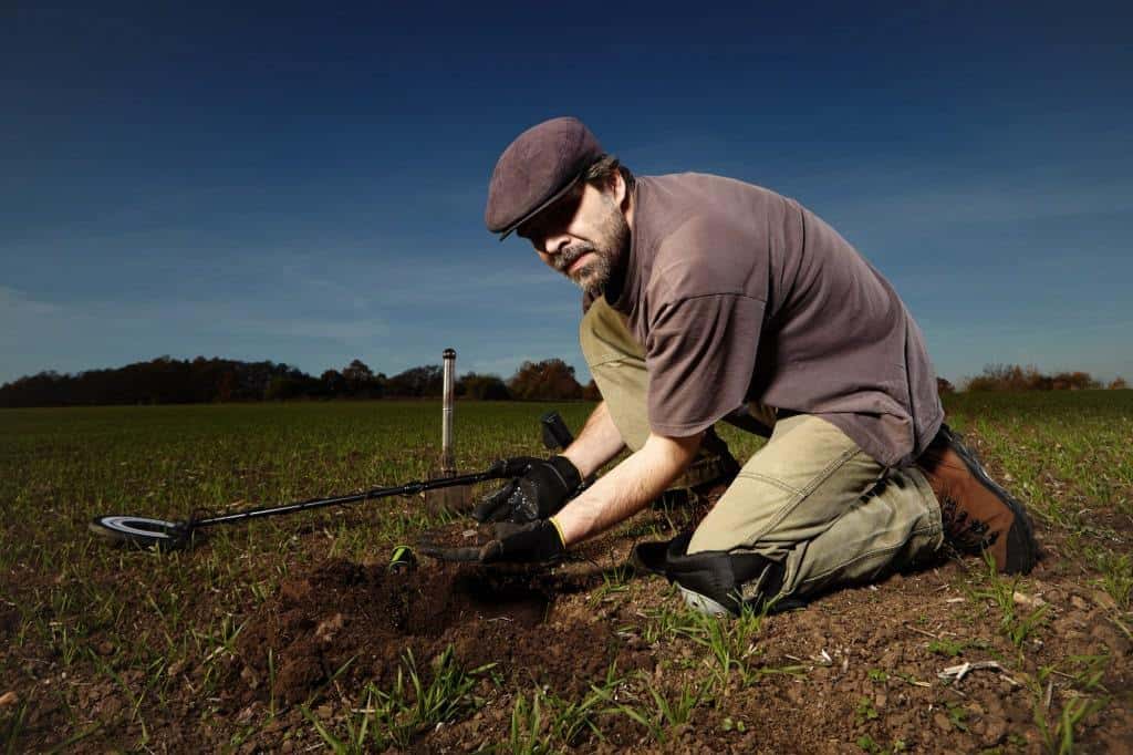 Amateur archeologist with metal detector in field