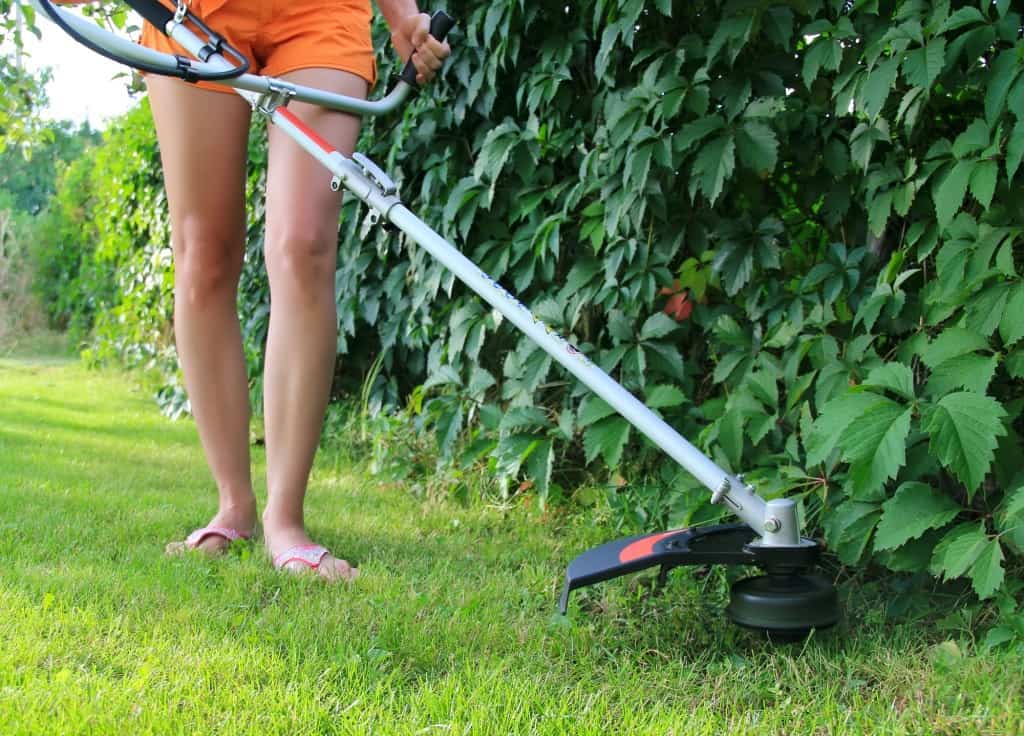 Girl triiming with a weed wacker