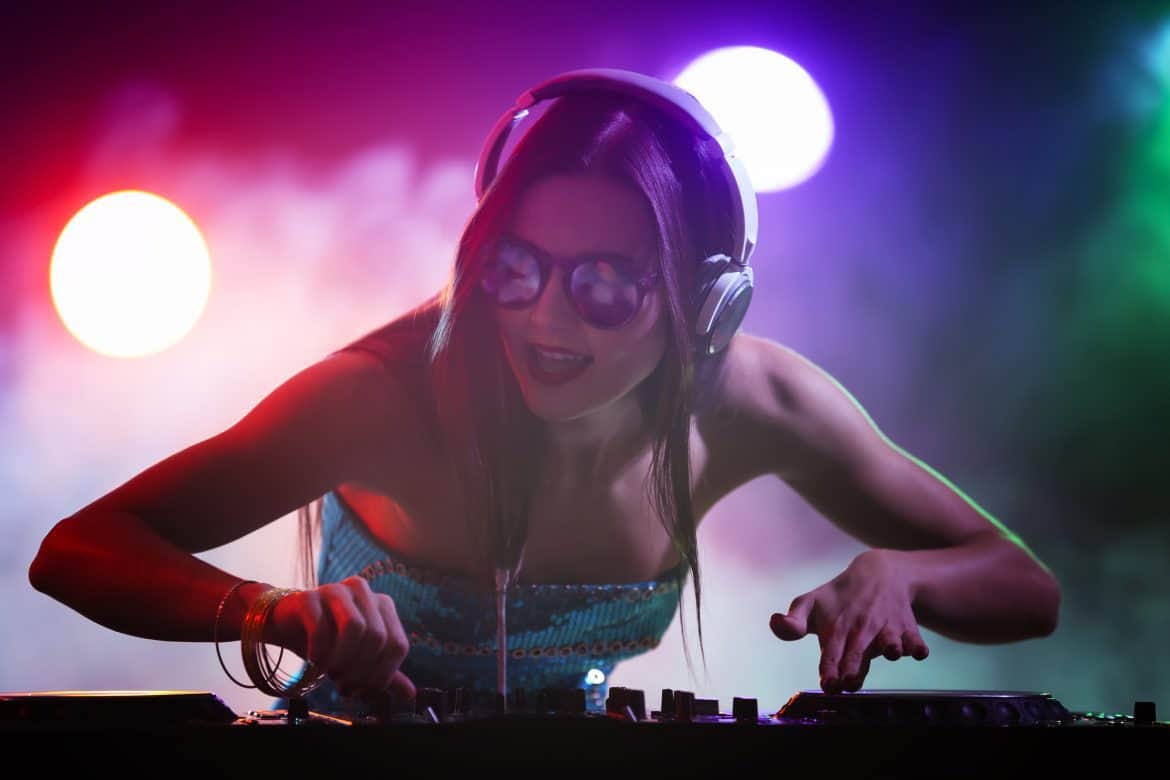 Pretty young DJ playing music in nightclub