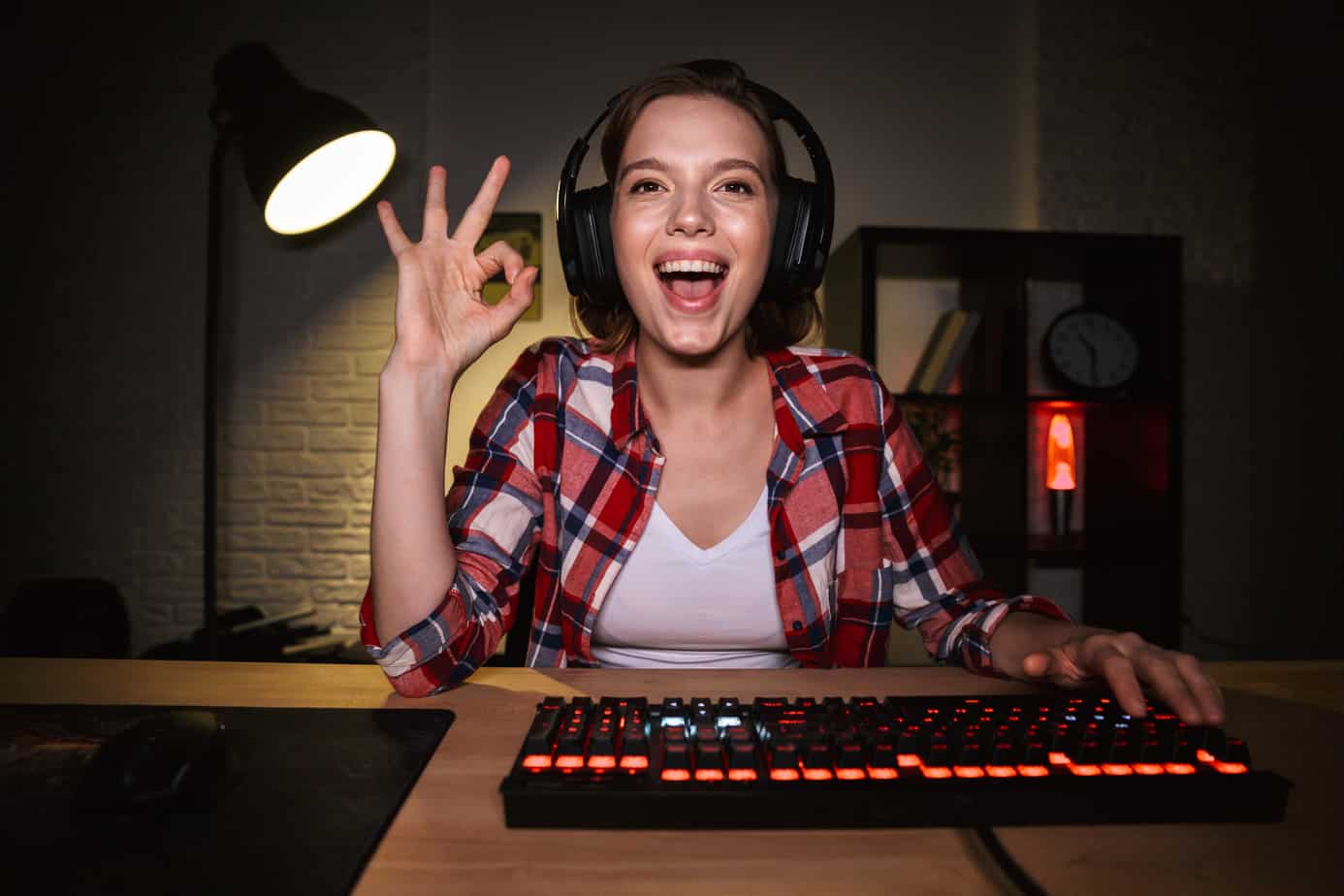 Excited girl gamer sitting at the table, playing online games